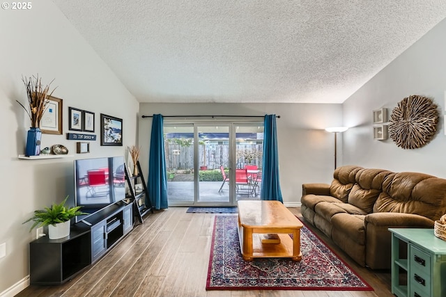 living room featuring lofted ceiling, hardwood / wood-style floors, and a textured ceiling