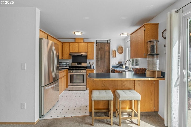 15205 NE 47th St, Vancouver, WA 98682 - kitchen featuring stainless steel appliances, a peninsula, under cabinet range hood, a kitchen breakfast bar, and brown cabinetry