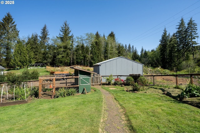 view of outdoor structure with fence, an outbuilding, and a vegetable garden