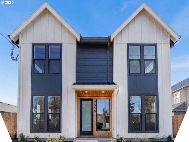 modern inspired farmhouse featuring a standing seam roof, metal roof, board and batten siding, and fence