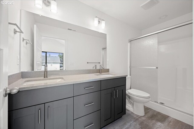 full bathroom featuring a stall shower, toilet, wood finished floors, and double vanity
