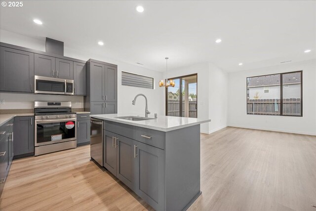 kitchen with a sink, stainless steel dishwasher, a chandelier, light wood-style floors, and light countertops