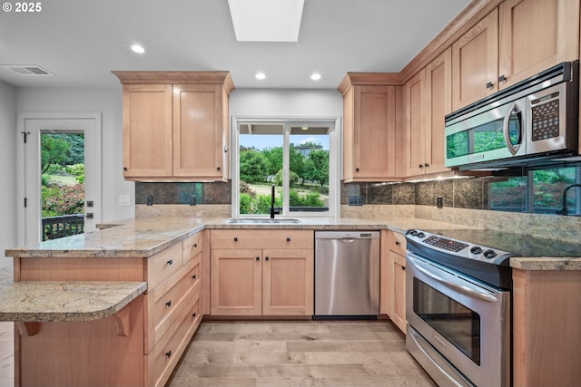 1908 50th St, Washougal, WA 98671 - kitchen featuring appliances with stainless steel finishes, a peninsula, light brown cabinetry, light wood-style flooring, and healthy amount of natural light