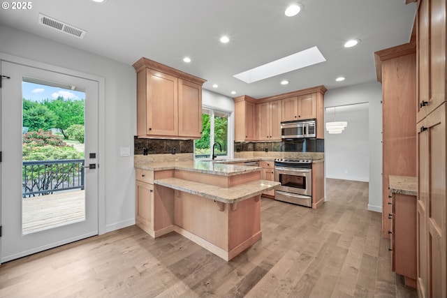 1908 50th St, Washougal, WA 98671 - kitchen with stainless steel appliances, a skylight, a peninsula, tasteful backsplash, and recessed lighting