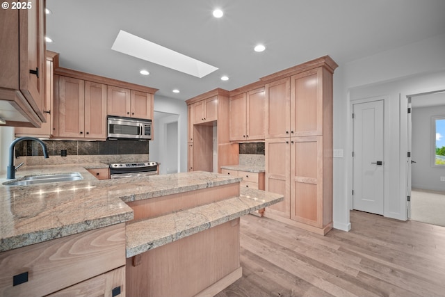 1908 50th St, Washougal, WA 98671 - kitchen with stainless steel appliances, a skylight, light wood-style flooring, tasteful backsplash, and a peninsula