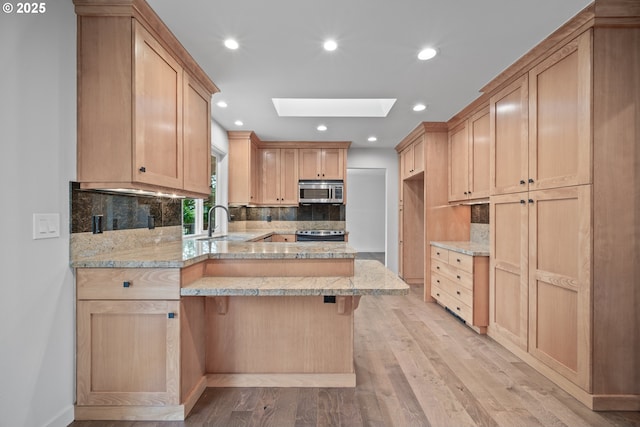 1908 50th St, Washougal, WA 98671 - kitchen featuring a peninsula, a skylight, light brown cabinetry, light wood-style flooring, and recessed lighting