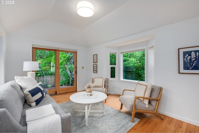 living area featuring vaulted ceiling, wood finished floors, and baseboards