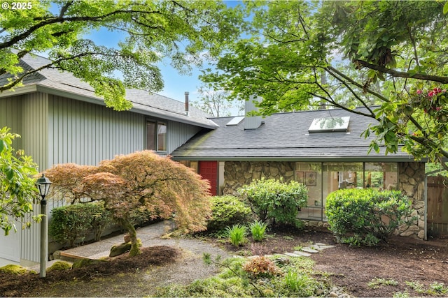 view of front of house featuring stone siding and roof with shingles