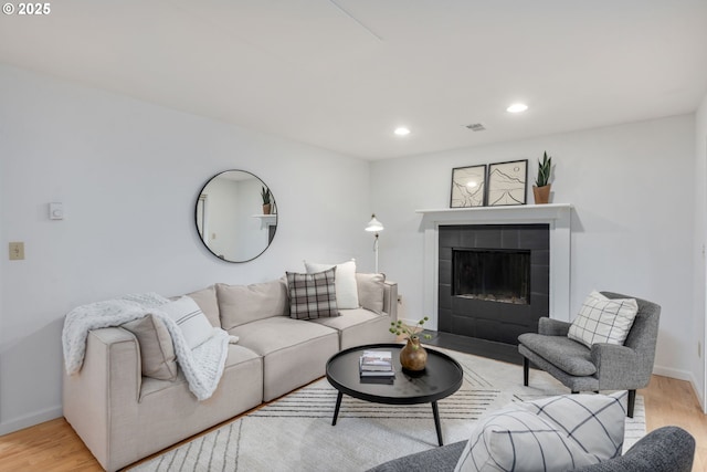 living area featuring wood finished floors, a fireplace, baseboards, and recessed lighting