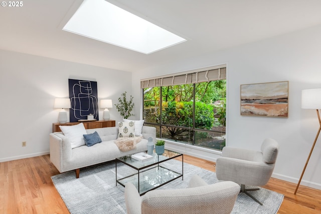living area with wood finished floors, a skylight, and baseboards