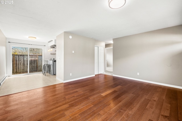 unfurnished living room with baseboards and wood-type flooring