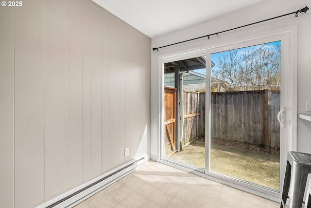 spare room featuring a baseboard heating unit, wooden walls, and light floors