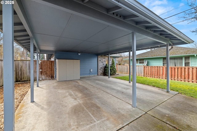 view of patio / terrace featuring a carport, a shed, fence, and an outbuilding