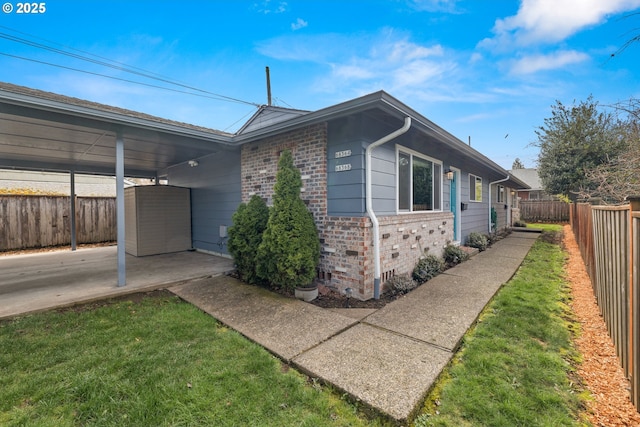 view of side of home featuring a patio, a fenced backyard, a storage shed, an outdoor structure, and brick siding