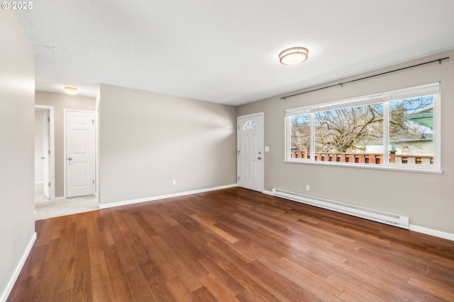 entrance foyer featuring a textured ceiling, a baseboard heating unit, baseboards, and wood finished floors