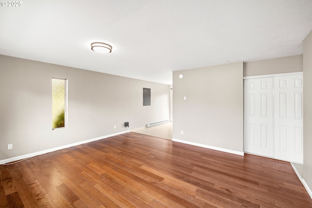 unfurnished room featuring baseboard heating, baseboards, and wood finished floors