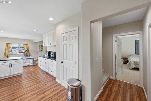kitchen with wood finished floors, white cabinets, dark countertops, recessed lighting, and baseboards
