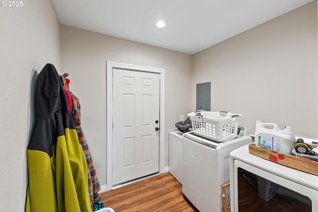 clothes washing area with washing machine and dryer, electric panel, light wood finished floors, and recessed lighting