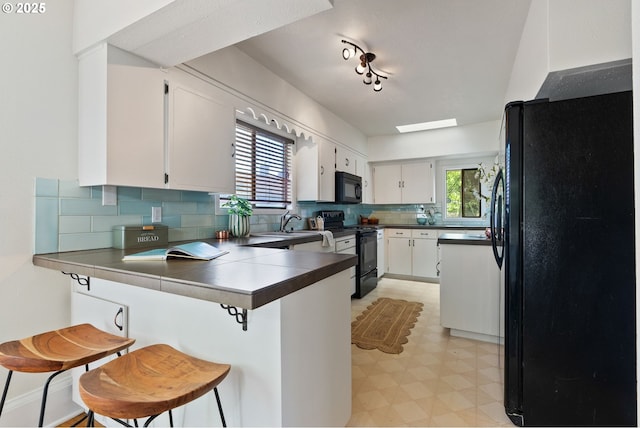 5655 SW Lombard Ave, Beaverton, OR 97005 - kitchen featuring black appliances, a peninsula, light flooring, tasteful backsplash, and a kitchen breakfast bar