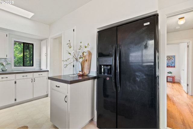 5655 SW Lombard Ave, Beaverton, OR 97005 - kitchen with black refrigerator with ice dispenser, dark countertops, white cabinets, and a skylight