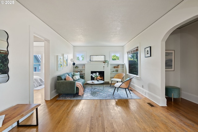 5655 SW Lombard Ave, Beaverton, OR 97005 - living area featuring wood finished floors, a fireplace, arched walkways, ornamental molding, and a textured ceiling