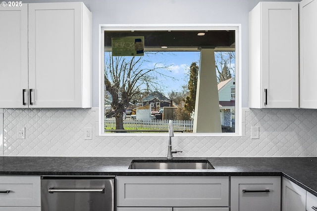 kitchen with dark countertops, white cabinetry, and a sink