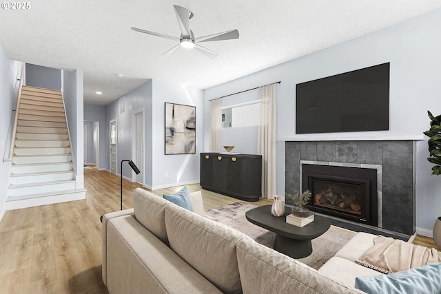 living room with a fireplace, stairway, ceiling fan, wood finished floors, and baseboards