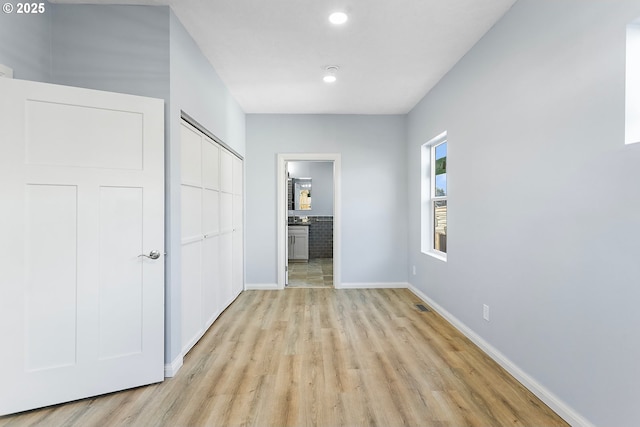 unfurnished bedroom with recessed lighting, a closet, light wood-style flooring, connected bathroom, and baseboards