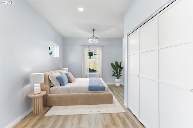 bedroom featuring a closet, light wood-style flooring, and baseboards