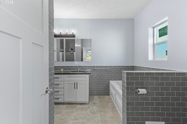 full bathroom featuring a garden tub, tile walls, wainscoting, vanity, and tiled shower