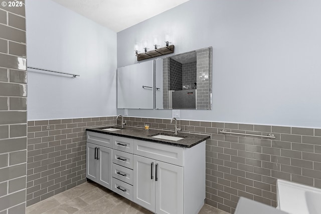 full bath featuring wainscoting, a sink, tile walls, and double vanity