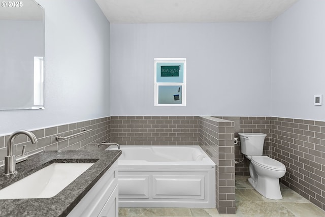 full bath with tile walls, toilet, wainscoting, vanity, and a bath