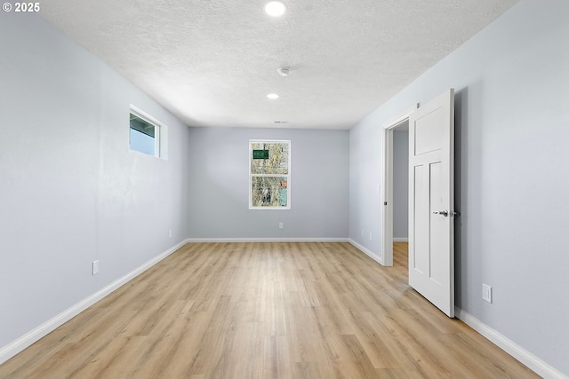 unfurnished room featuring light wood-style flooring, baseboards, and a textured ceiling