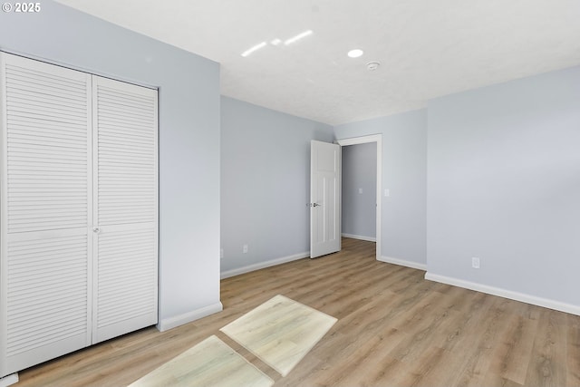 unfurnished bedroom featuring a closet, baseboards, and light wood finished floors