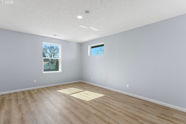 spare room with baseboards, light wood-style floors, and a healthy amount of sunlight