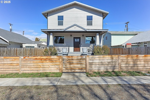 view of front of house with covered porch, a fenced front yard, and a gate