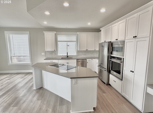 414 Hedin Ter, Gaston, OR 97119 - kitchen featuring appliances with stainless steel finishes, a sink, light wood-type flooring, white cabinets, and a textured ceiling