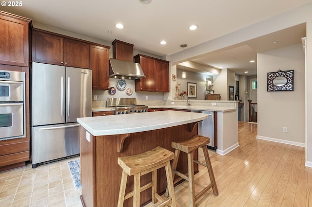 8867 SE 13th Ave, Portland, OR 97202 - kitchen featuring appliances with stainless steel finishes, a peninsula, wall chimney range hood, light countertops, and recessed lighting