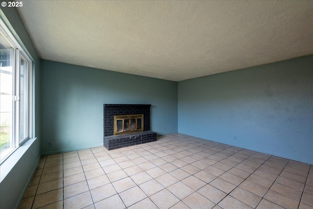 unfurnished living room featuring a textured ceiling, a brick fireplace, and light tile patterned flooring