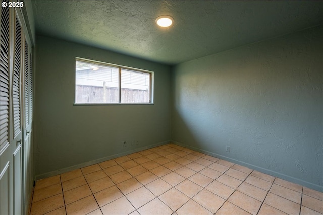 spare room with light tile patterned floors and a textured ceiling