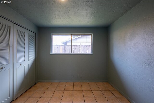 unfurnished bedroom featuring a closet, light tile patterned floors, and a textured ceiling