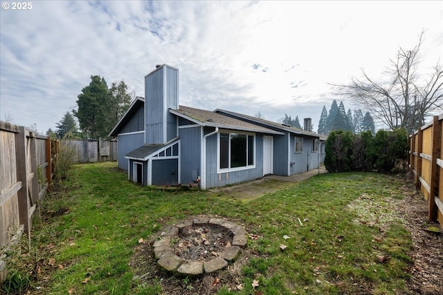 back of house featuring a fire pit and a lawn