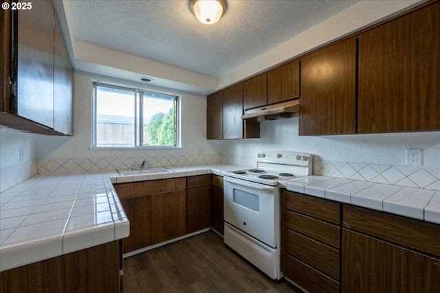 kitchen featuring white range with electric cooktop, sink, dark hardwood / wood-style floors, a textured ceiling, and tile counters