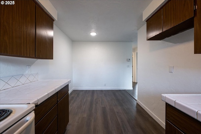 kitchen with tile countertops, dark hardwood / wood-style floors, dark brown cabinetry, and electric stove