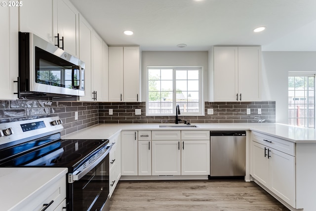 2977 Dry Creek Rd, Eugene, OR 97404 - kitchen with appliances with stainless steel finishes, a sink, a peninsula, light countertops, and white cabinetry