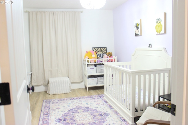 bedroom with a crib and wood finished floors