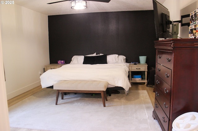 bedroom with light wood finished floors, a ceiling fan, and baseboards