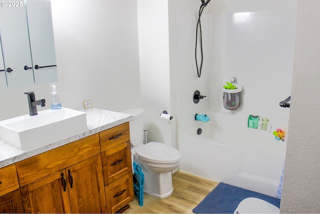 bathroom featuring toilet, vanity, wood finished floors, and bathing tub / shower combination