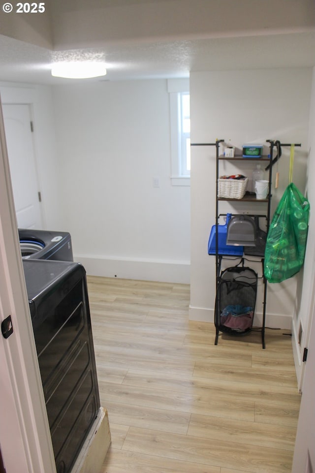 clothes washing area featuring baseboards, laundry area, and light wood-style floors