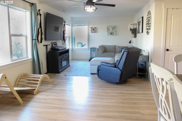 living room with baseboards, light wood-style flooring, and a ceiling fan